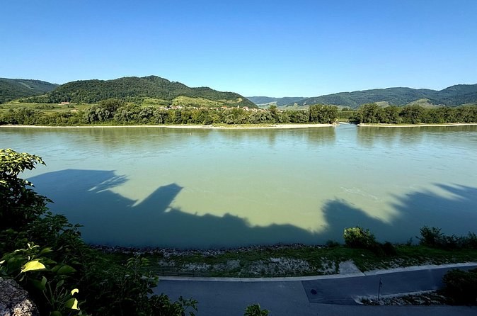 The broad green Danube and the wooded hills of the far bank on a clear day