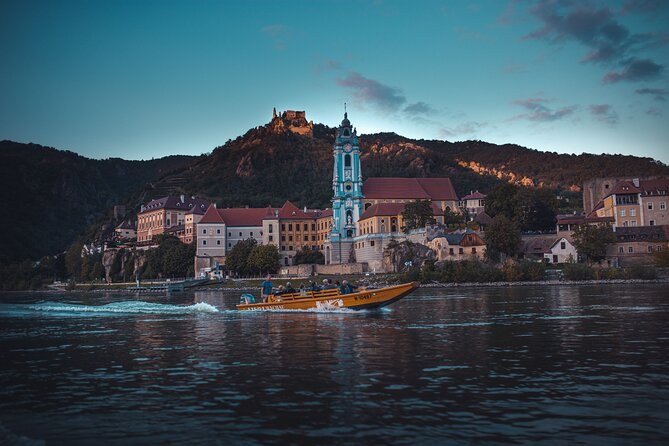 Dürnstein at dusk from the river, a boat passing below the blue tower