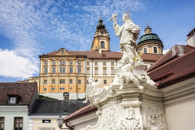 Melk Abbey's towers and dome rising behind a white baroque statue in the town